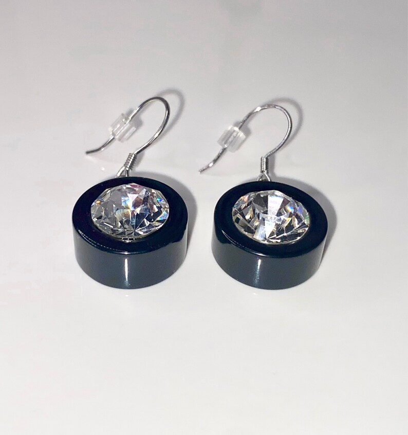 May include: A pair of black and silver earrings with a large clear crystal in the center of each earring.