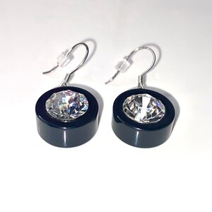 May include: A pair of black and silver earrings with a clear crystal in the center of each earring.