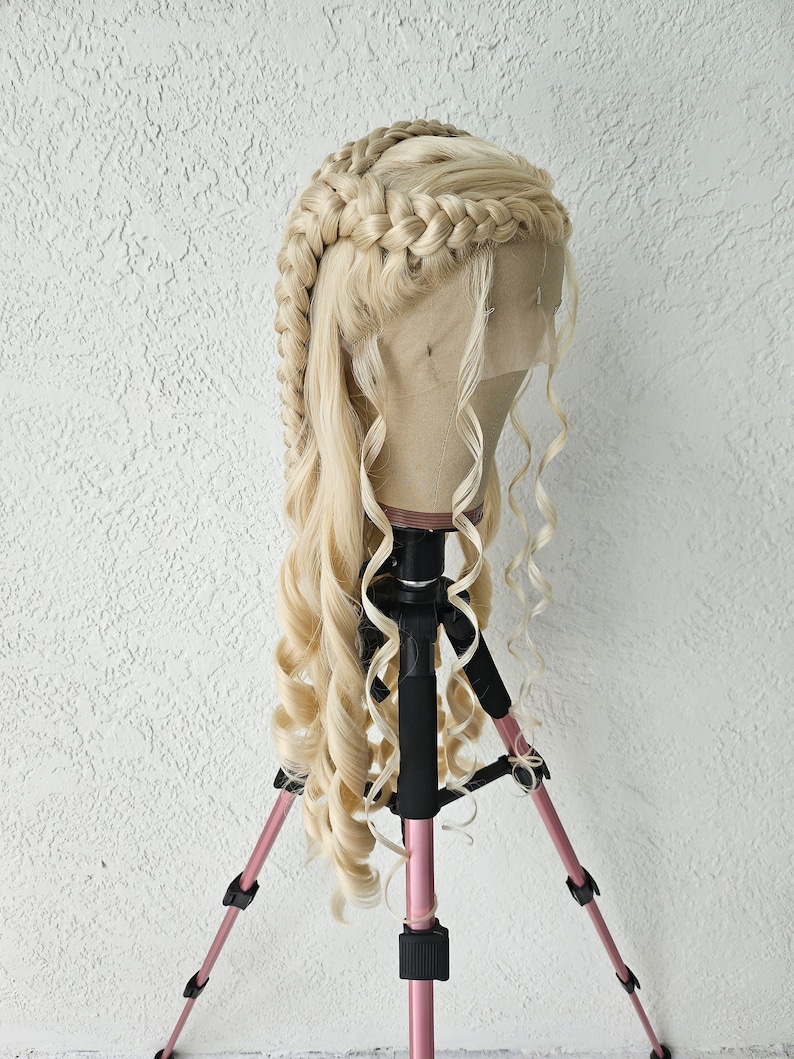 May include: A blonde wig with two braids and long, loose curls. The wig is on a tripod stand.