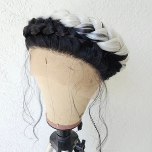 May include: A black and white wig with a braided crown on a mannequin head. The wig is styled with long, loose waves.