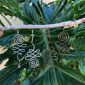 May include: Three pairs of silver and bronze wire earrings with a spiral design. The earrings are hanging from a branch.