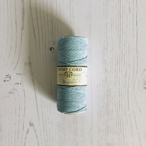 May include: A spool of light blue hemp cord with a label that reads "HEMP CORD" and "PREMIUM QUALITY" in a gold and black font.