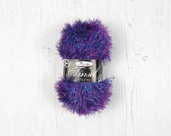 May include: A ball of purple and blue tinsel yarn with a silver label that reads "King Cole Tinsel Chunky".