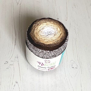 Może przedstawiać: Kulka brązowej, beżowej i białej przędzy z białą etykietą z napisem "Relwisst Chainy Cotton CAKE" i małym logo igły i przędzy.