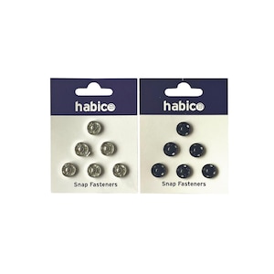 Peut inclure: Deux paquets de boutons pression, l'un avec des boutons argentés et l'autre avec des boutons noirs. Chaque paquet porte l'inscription "habico" et "Boutons pression".