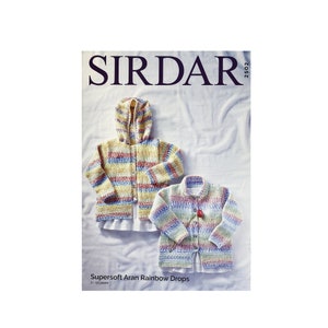 May include: A knitting pattern booklet from Sirdar featuring two colorful striped cardigans for children. The pattern is called "Supersoft Aran Rainbow Drops" and is for ages 2-3 years.