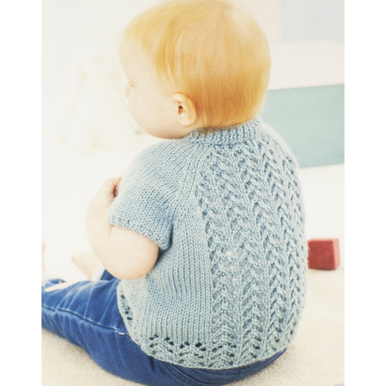 May include: A light blue knitted baby sweater with a delicate lace pattern on the back.