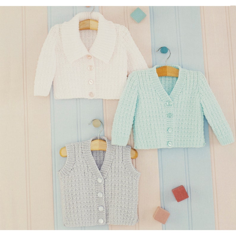 May include: Three knitted baby garments: a white cardigan with a collar, a light blue cardigan, and a gray vest. All garments have button closures.