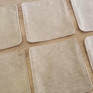 Pode incluir: Seis  tapetes quadrados de tecido bege. Os tapetes são feitos de um tecido tecido com uma textura sutil.