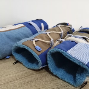 Könnte beinhalten: Drei blaue und braune Stoffröhren mit weichem, flauschigem Futter. Die Röhren sind aus verschiedenen gemusterten Stoffen gefertigt und haben einen Reißverschluss.
