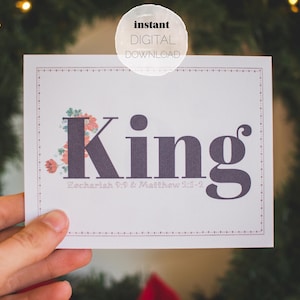 May include: A white printable card with the word "King" in large, dark gray letters. The word is decorated with small red and green flowers. The text "Zechariah 9:9 & Matthew 2:2" is printed below the word "King".