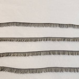 May include: Four rows of black eyelash trim with a fringe of short, black hairs.
