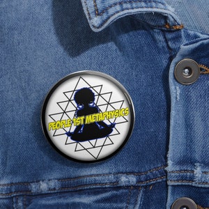 May include: A black and white button with a silhouette of a person sitting in a meditative pose. The person is surrounded by a geometric pattern. The text "PEOPLE 1ST METAPHYSICS" is written in yellow letters around the person.