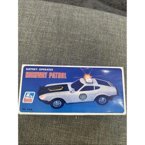 May include: Vintage toy police car in a box. The box is blue with the words "HIGHWAY PATROL" in red and white. The toy car is white with a black hood and a flashing light on top. The box also says "BATTERY OPERATED".