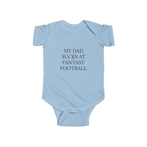 May include: Light blue baby onesie with the text "My Dad Sucks at Fantasy Football" printed in black.