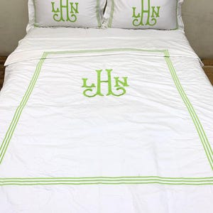 Puede incluir: Juego de cama blanco con ribete bordado y monograma en verde. El juego incluye dos fundas de almohada y una funda n&oacute;rdica, todo con una est&eacute;tica limpia. El bordado verde proporciona un toque de color sobre la tela blanca.