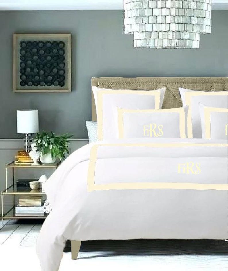 May include: White bedding with a cream colored border and the monogram "FKS" embroidered on the pillow and duvet cover.
