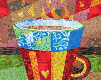 Puede incluir: Una taza de patchwork colorida con un diseño rojo, amarillo y azul. La taza está llena de un líquido marrón y tiene un diseño en forma de corazón en el lateral.