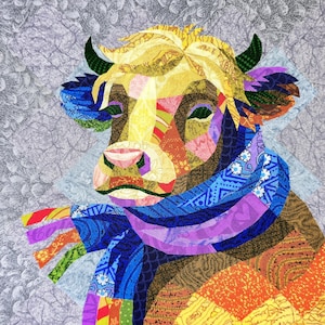 May include: A patchwork cow illustration featuring a blue scarf and horns. The cow's face is constructed from fabric scraps in yellow, orange, blue, purple, and brown. The background is a textured grey fabric.