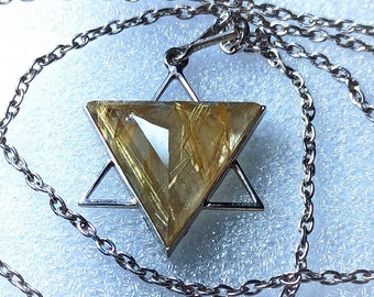 May include: A silver necklace featuring a pendant in the shape of a Star of David. The pendant has a clear, triangular gemstone with golden inclusions. The chain is a delicate silver link design, creating a simple yet elegant accessory.