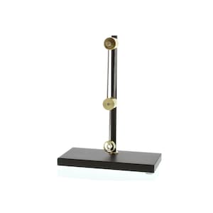 May include: A black wooden base with a vertical metal rod and three brass pulleys. The pulleys are attached to the rod and have a string running through them.
