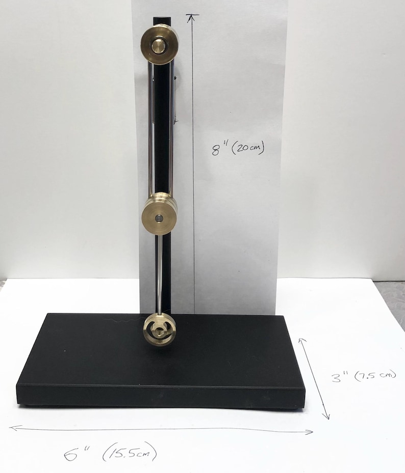 May include: A black metal stand with a silver rod and three brass wheels. The stand is 6 inches wide, 3 inches deep, and 8 inches tall.