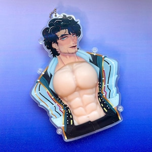 May include: A clear acrylic keychain featuring a stylized illustration of a man with dark hair and blue eyes, wearing an open blue and gold striped shirt. The keychain has a sculpted torso with defined abdominal muscles.