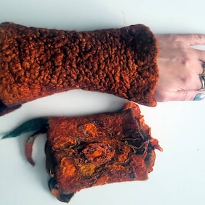 May include: A pair of orange and brown felted wool wrist warmers. One is plain and the other has a floral design.