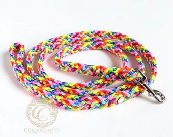 May include: A multi-colored braided rope leash featuring a vibrant rainbow pattern of red, orange, yellow, green, blue, and purple strands. The leash includes a silver-toned metal swivel snap hook at one end and a loop handle at the other end.