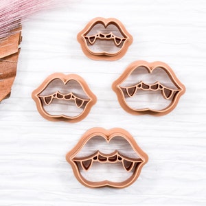 May include: Set of three brown plastic cookie cutters shaped like a vampire's mouth with fangs.