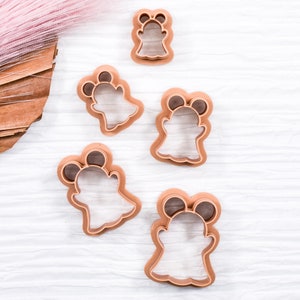 May include: Set of five brown plastic ghost cookie cutters of varying sizes. The cutters are on a white wooden surface.