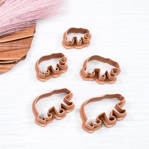 May include: Set of four brown plastic bear cookie cutters of varying sizes.