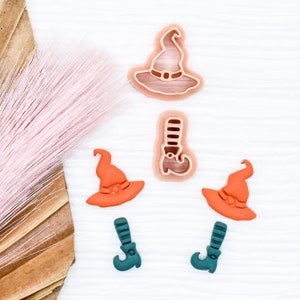 May include: Set of five Halloween-themed cookie cutters. The set includes two witch hats, one witch boot, and two green witch shoes. The witch hats and boot are pink, and the shoes are green.