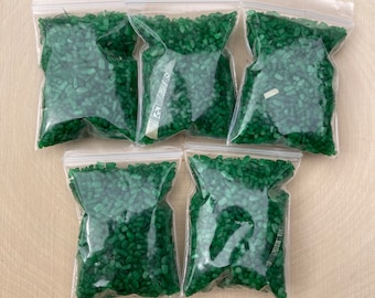 May include: Six small clear plastic bags filled with green glass beads. The bags are sealed with a zipper.