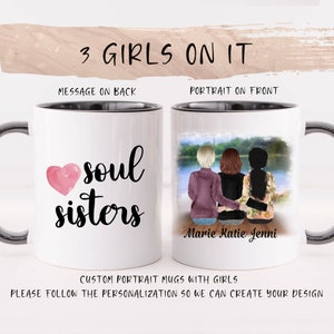 Puede incluir: Taza de cerámica blanca con borde y asa negros. La taza tiene un corazón rosa con el texto "soul sisters" en la parte posterior. La parte delantera de la taza tiene una ilustración de acuarela de tres mujeres sentadas en un muelle con un lago en el fondo. El texto "Marie Katie Jenni" está debajo de la ilustración.