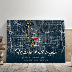May include: A navy blue canvas print with a map of a city. A red heart is placed on the map with the text "Where it all began" in white cursive writing. The text "Joseph & Christina - July 2022" and the coordinates "39 46 6.2472" N 86 9 29.0376" W" are printed below the cursive text.