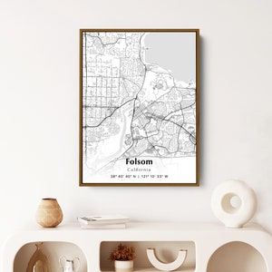 May include: A black and white map print of Folsom, California with a gold frame. The map shows the city streets and landmarks. The text "Folsom, California" and the coordinates "38° 40' 40" N | 121° 10' 33" W" are printed below the map.