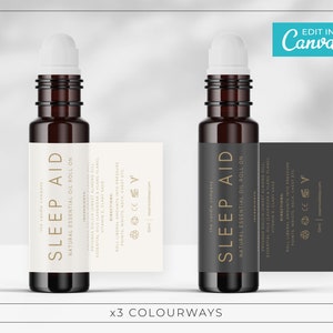 Op de afbeelding: Twee bruine glazen flessen met witte en zwarte etiketten. De etiketten hebben gouden letters en zeggen "SLEEP AID" en "NATURAL ESSENTIAL OIL ROLL ON".