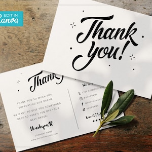 May include: Two white thank you cards with black script text and decorative elements. One card reads "Thank You!" in large script. The other card includes a thank you message, discount code, and shop details. A sprig of green leaves rests on the cards.
