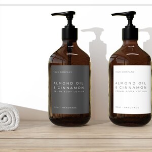 May include: Two amber glass bottles with pumps, each containing a vegan body lotion. The bottles have white labels with black text that reads "Almond Oil & Cinnamon Vegan Body Lotion" and "150ml Handmade".
