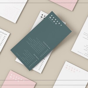 Puede incluir: Un men&uacute; verde con el texto "BAKERY MENU" en blanco. El men&uacute; est&aacute; colocado sobre una superficie marr&oacute;n claro con otros men&uacute;s en rosa y blanco.