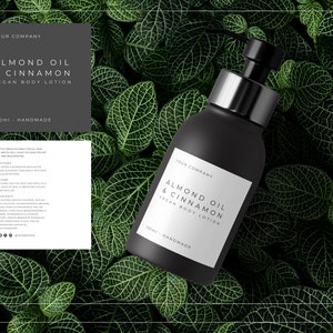 May include: A black bottle of almond oil and cinnamon vegan body lotion with a silver pump top. The bottle is sitting on a bed of green leaves. The label on the bottle reads "Your Company Almond Oil & Cinnamon Vegan Body Lotion 150ml - Handmade".