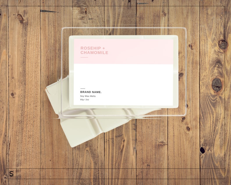 May include: A clear plastic container with a white label that reads "ROSEHIP + CHAMOMILE" in pink text. The label also includes the text "BRAND NAME. Soy Wax Melts 60g / 2 oz."