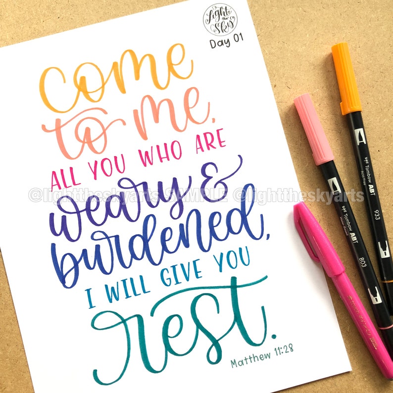 May include: A white paper with colorful calligraphy that reads "Come to me, all you who are weary & burdened, I will give you rest." The text is accompanied by three Tombow ABT markers in pink and orange.