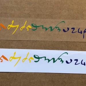 May include: Two rainbow-colored stickers with the same text. One sticker is on a clear background, and the other is on a white background. The text is in a handwritten style, with each word in a different color.