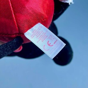 May include: Red and black plush toy with a white tag that says "CE".