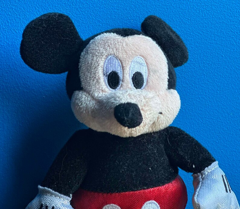 May include: A plush black and white Mickey Mouse toy with large black ears and a red and white polka dot bow tie.