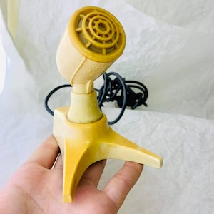 May include: A vintage yellow microphone with a black cord and a three-pronged base.