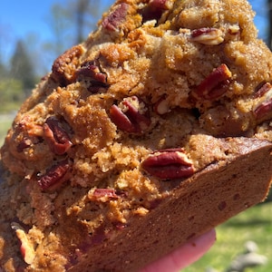 May include: A loaf of pecan bread with a golden brown crust and a generous amount of pecans on top.
