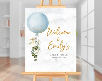 Puede incluir: Un cartel de bienvenida para un baby shower con un globo azul con purpurina dorada, hojas verdes y doradas, y el texto "Bienvenido a Emily's Baby Shower 17 de enero - 20XX".